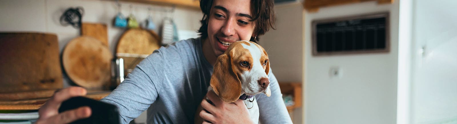 Young adult sitting holding dog and taking a selfie.